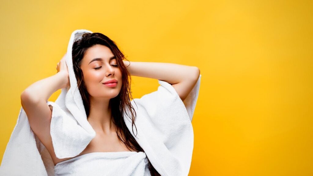 woman wearing white towel drying hair with another white towel