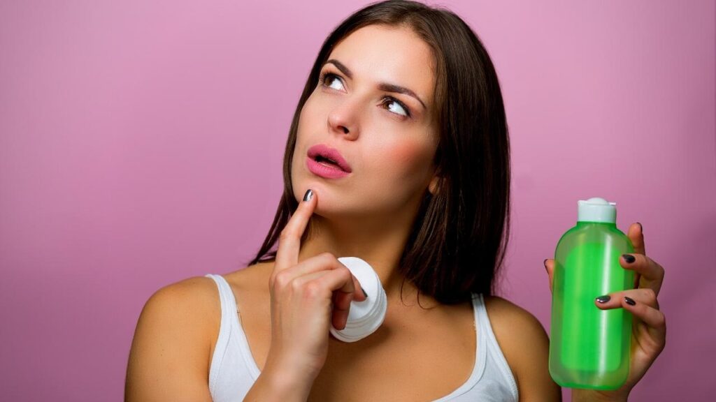woman contemplating while holding green shampoo bottle