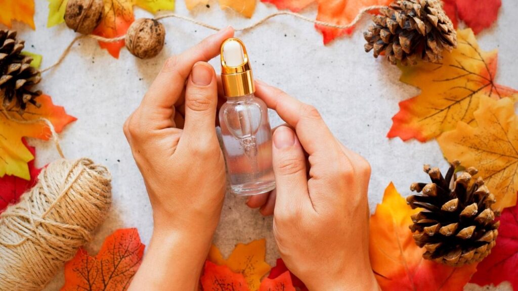 hands holding bottle of essential oils circled with leaves