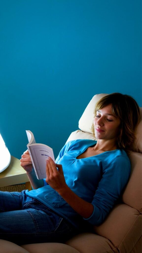 woman reading beside SAD light device