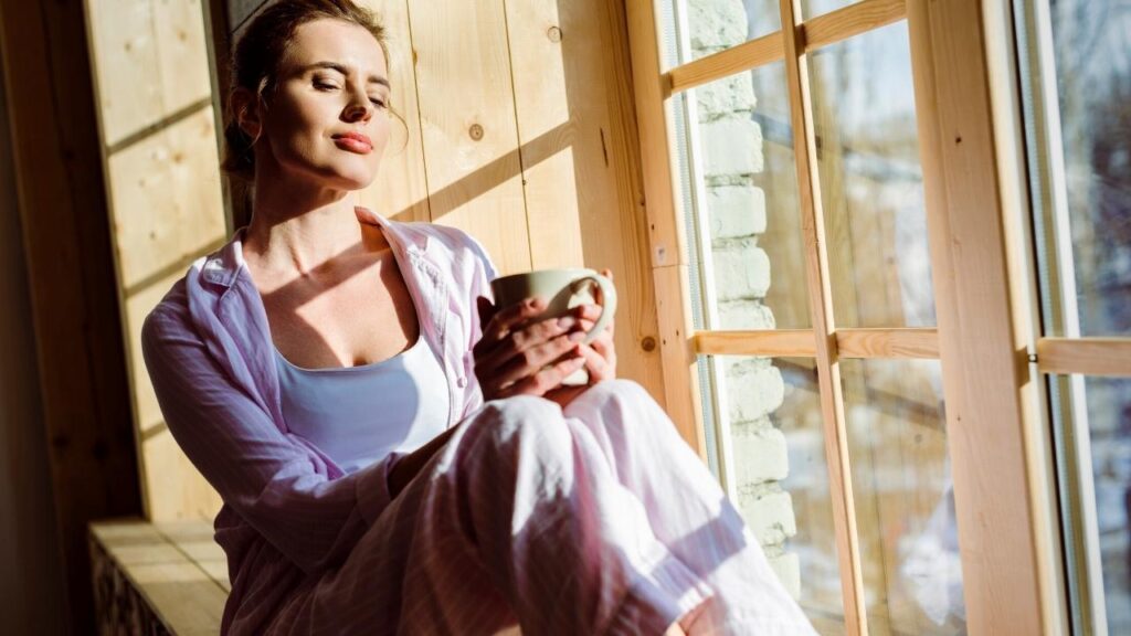 woman sitting enjoying natural sunlight from window