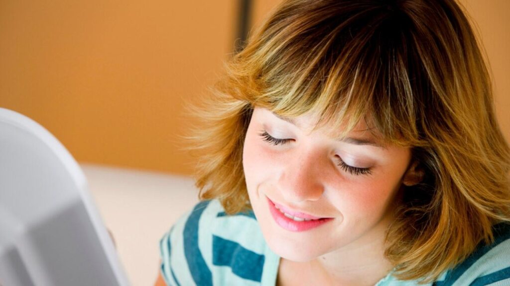 happy woman sitting beside light therapy device