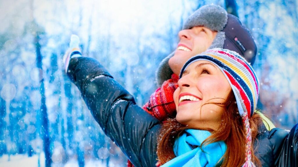 couple in winter hats looking up at sky