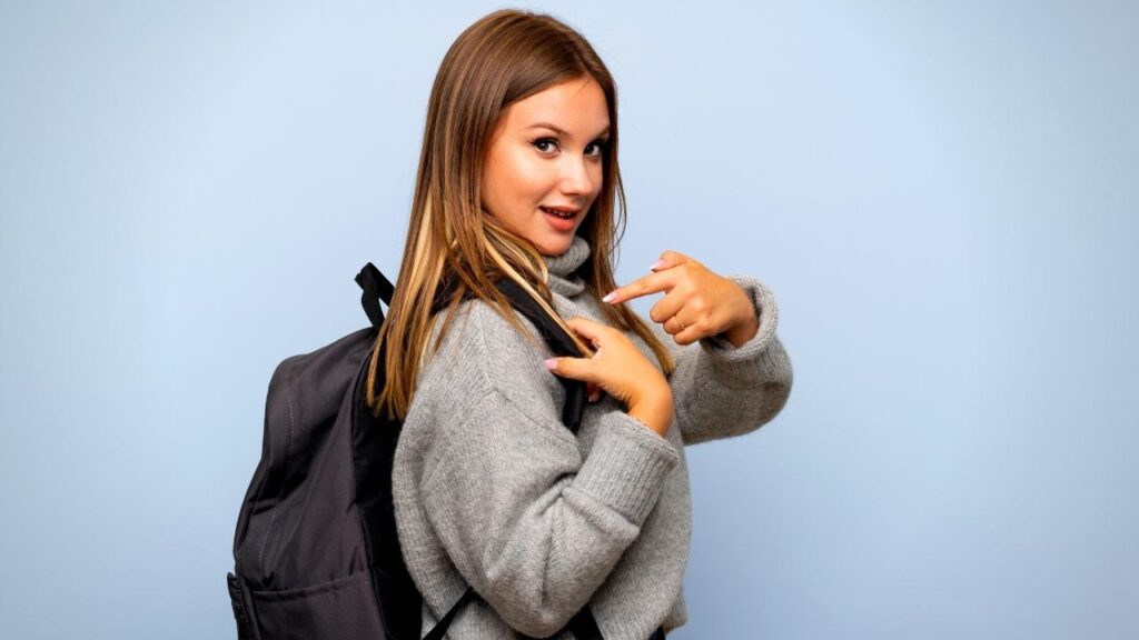 teenage girl pointing to her backpack