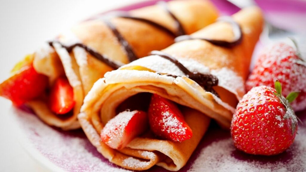 2 rolled up crepe pancakes and strawberries