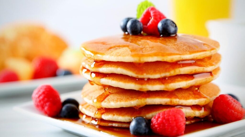 stack of pancakes with syrup and berries