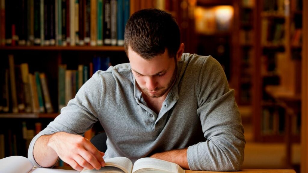 young man reading a book in the library