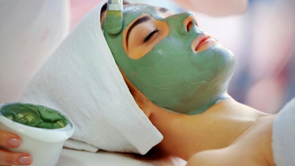 woman with green seaweed mask on face at spa