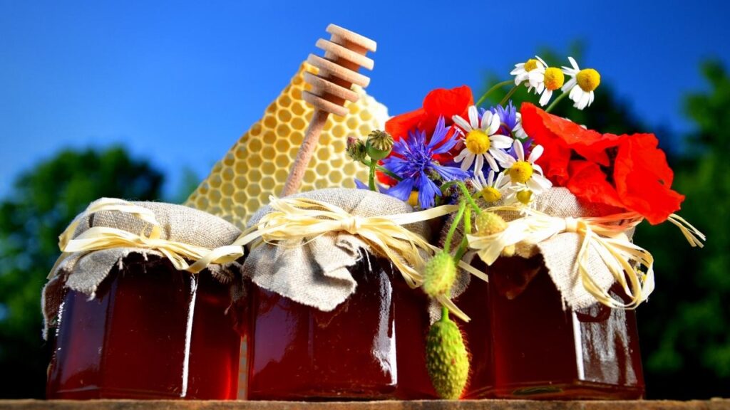 jars of honey, honeycomb and flowers