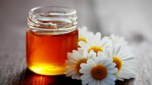 glass jar of manuka honey and chamomile flowers