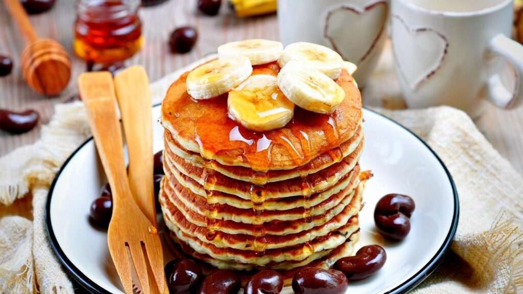 stack of pancakes on plate with bamboo cutlery
