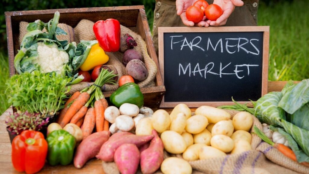 fruit and veg beside farmers market chalkboard sign