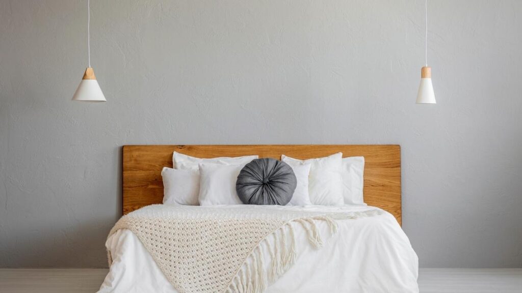 wooden bed against neutral wall with white bedding