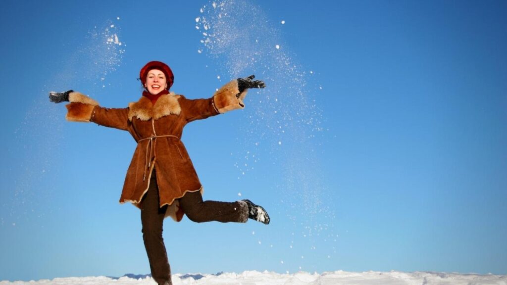 happy girl in brown coat jumping in snow
