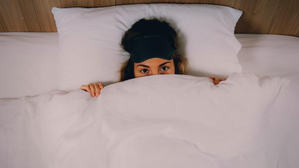 woman peeping over the white duvet