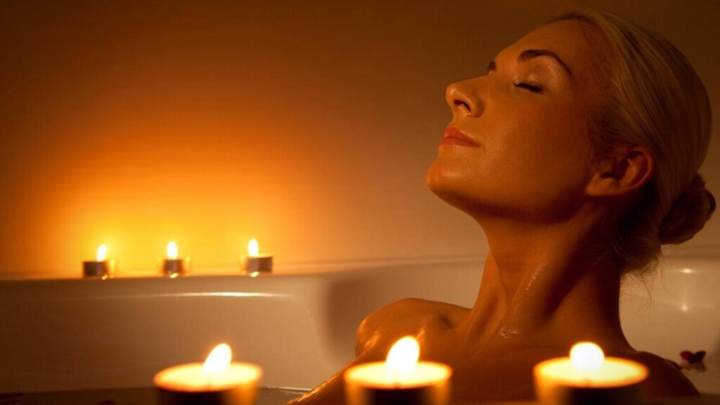 woman relaxing in bath surrounded by tealight candles
