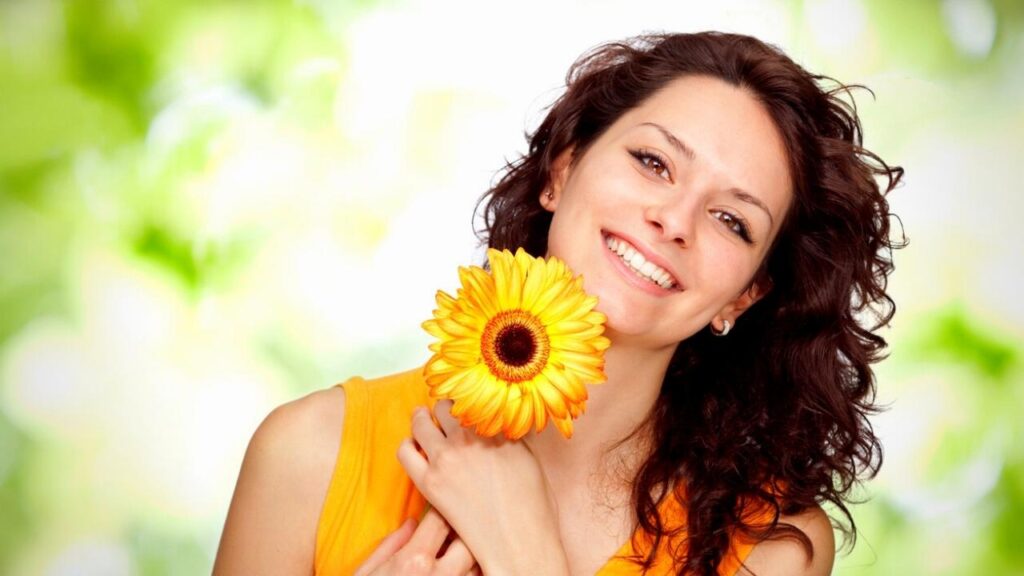 happy brunette woman holding yellow flower