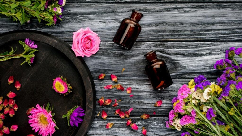 bottles of essential oils and pink flowers on table