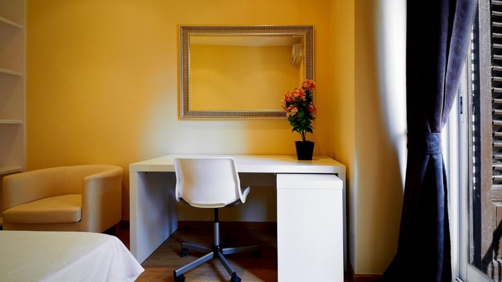 small white chair at white desk below mirror