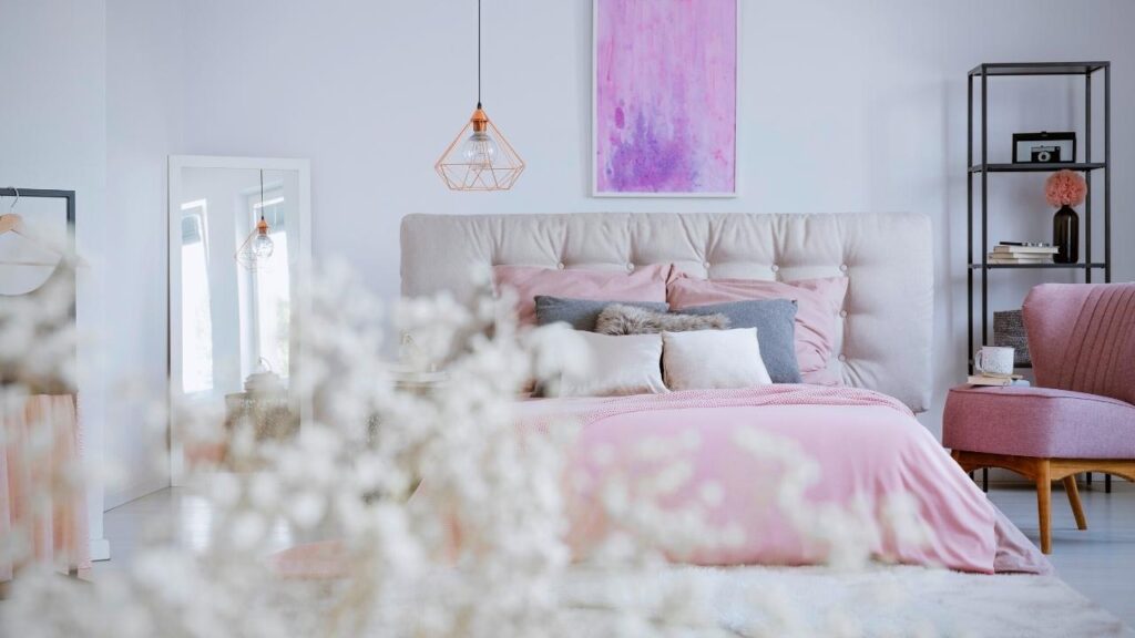 bed with large grey headboard and lots of cushions