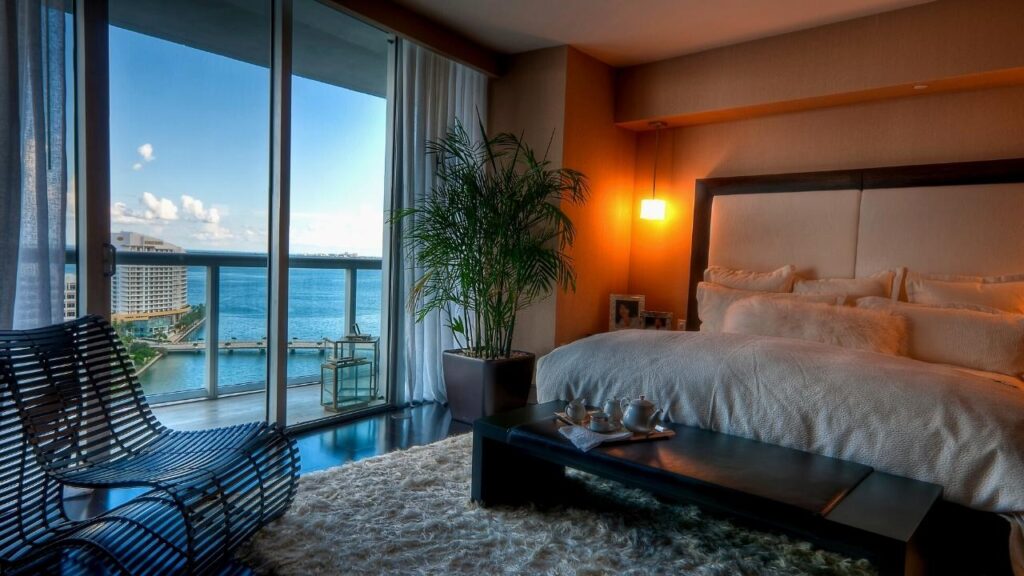 luxury bedroom with large plant, rug and sea view