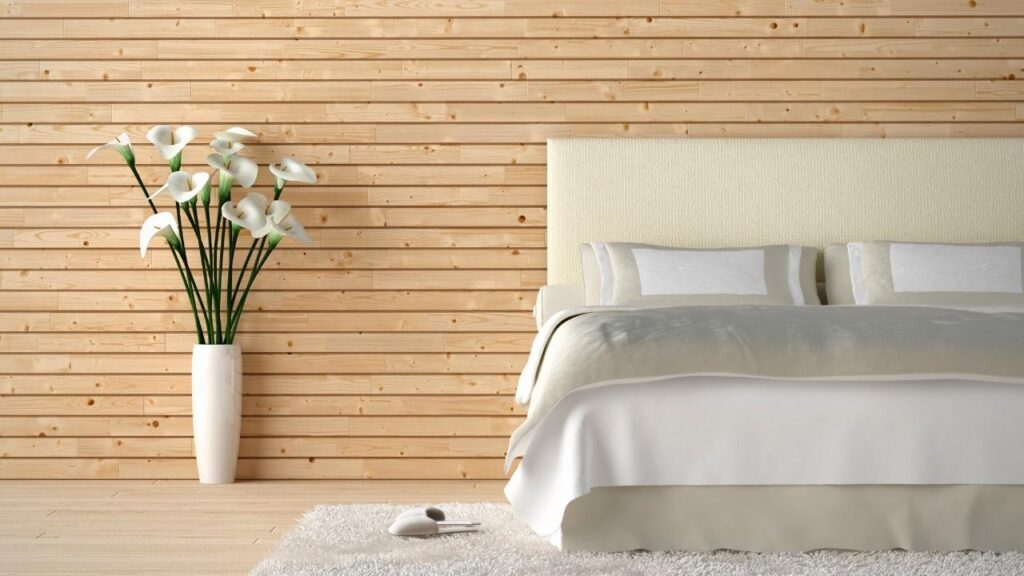 wood effect wall behind light coloured bed and vase of flowers