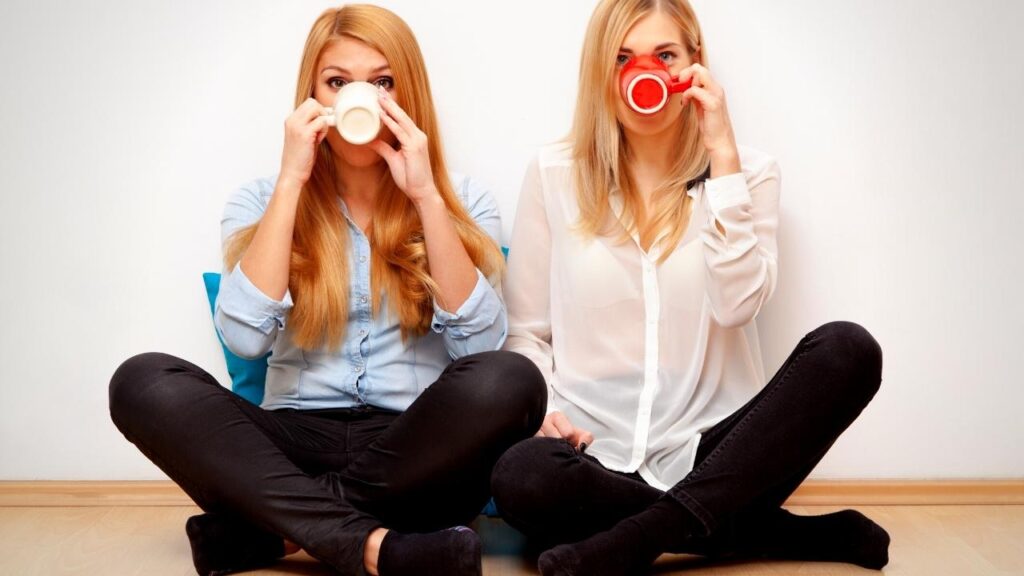 2 young blonde women sitting drinking tea