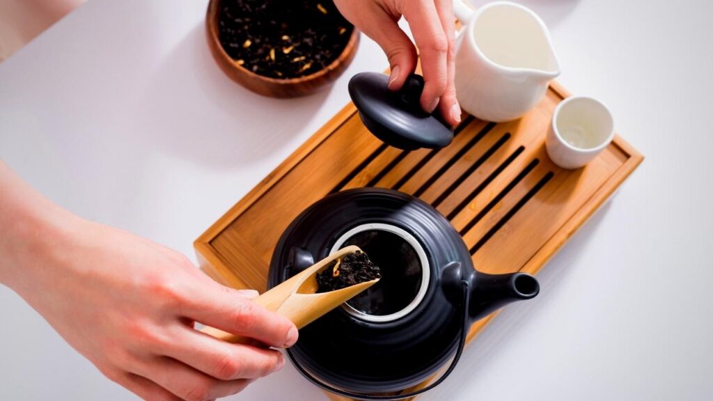 teabag being lifted from black teapot