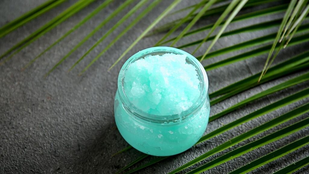 open tub of light blue body scrub on dark surface