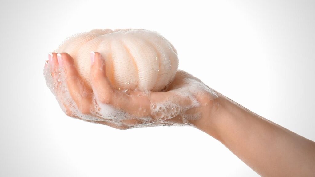 soapy hand holding a round loofah