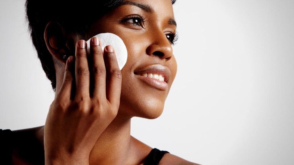 dark skinned woman applying skincare product