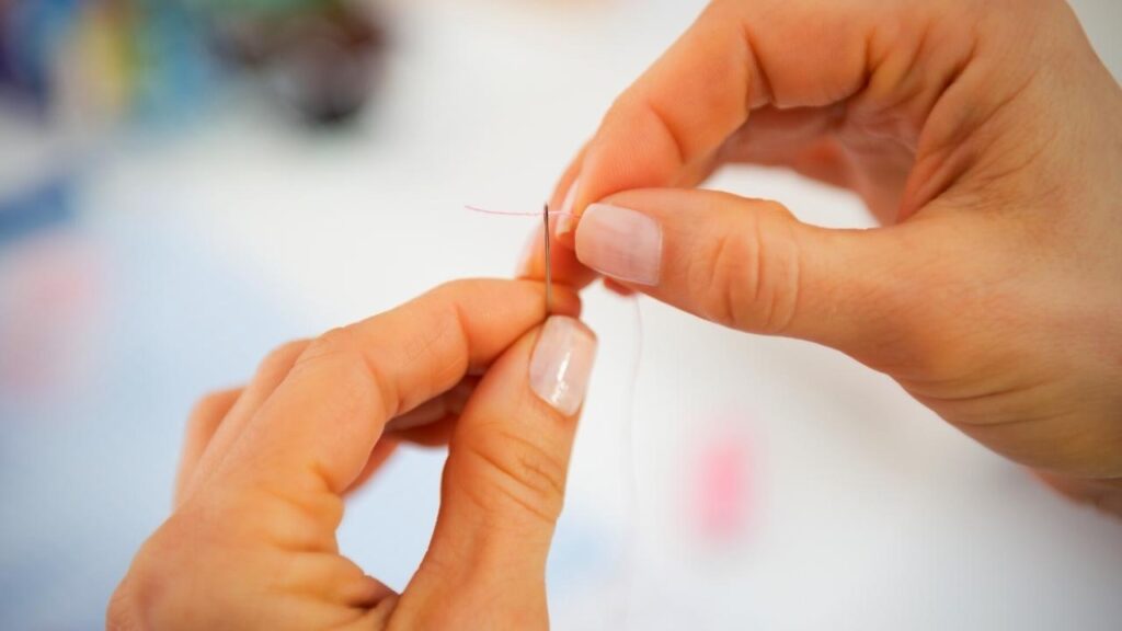 woman's hands threading needle