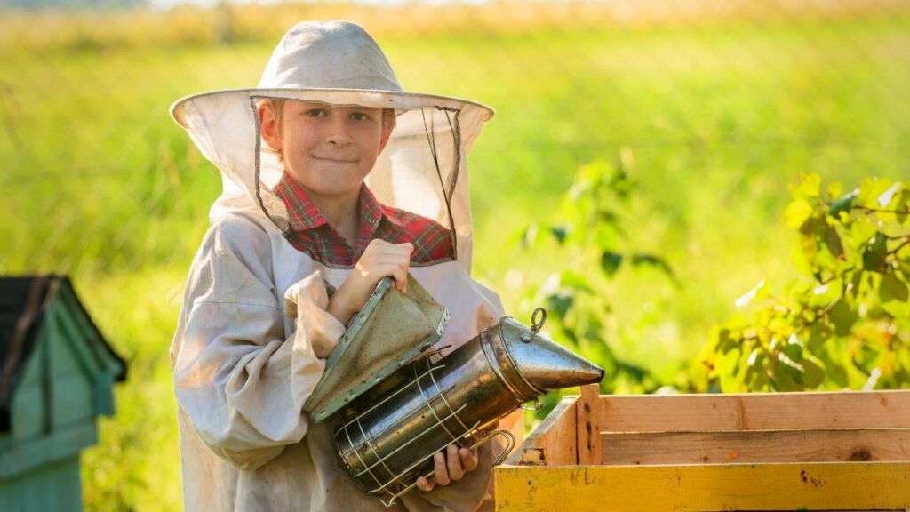 young beekeeper using bee smoker