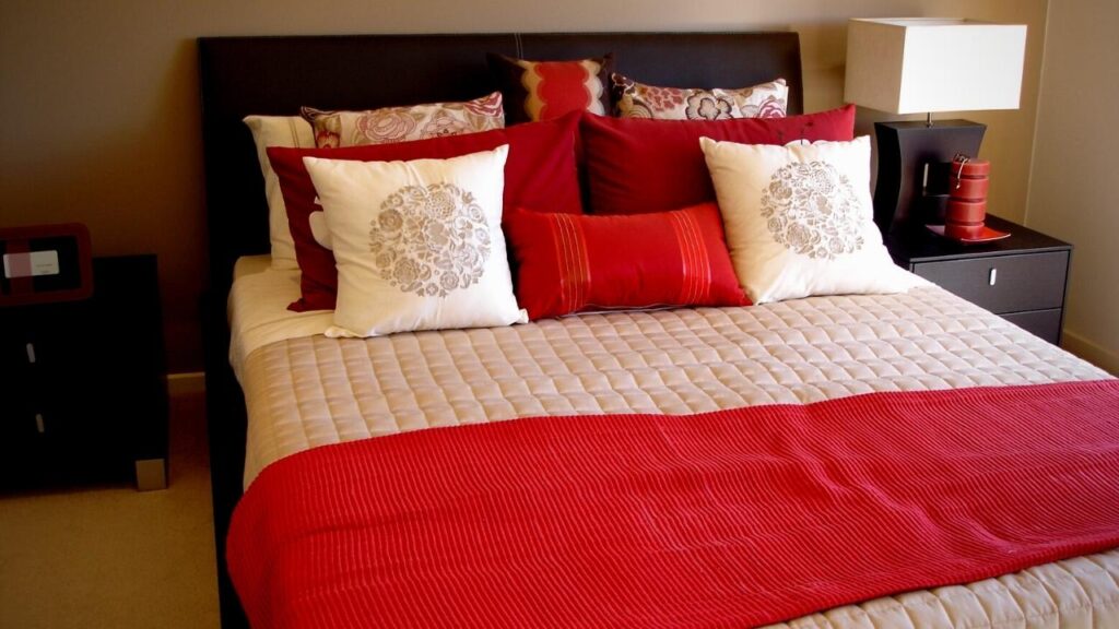 a double bed with red and white bedding