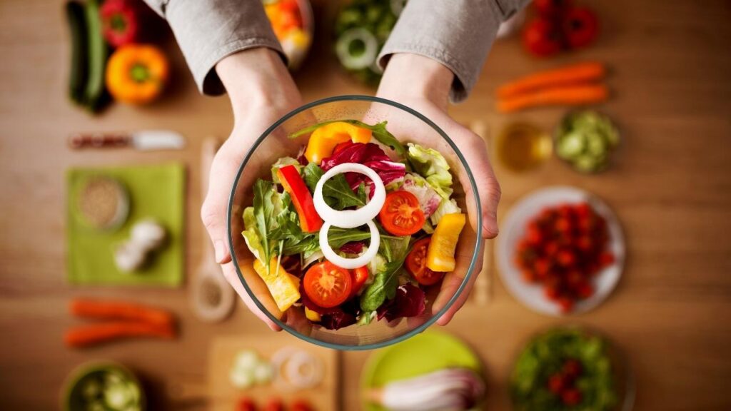 hands holding a plate of healthy salad