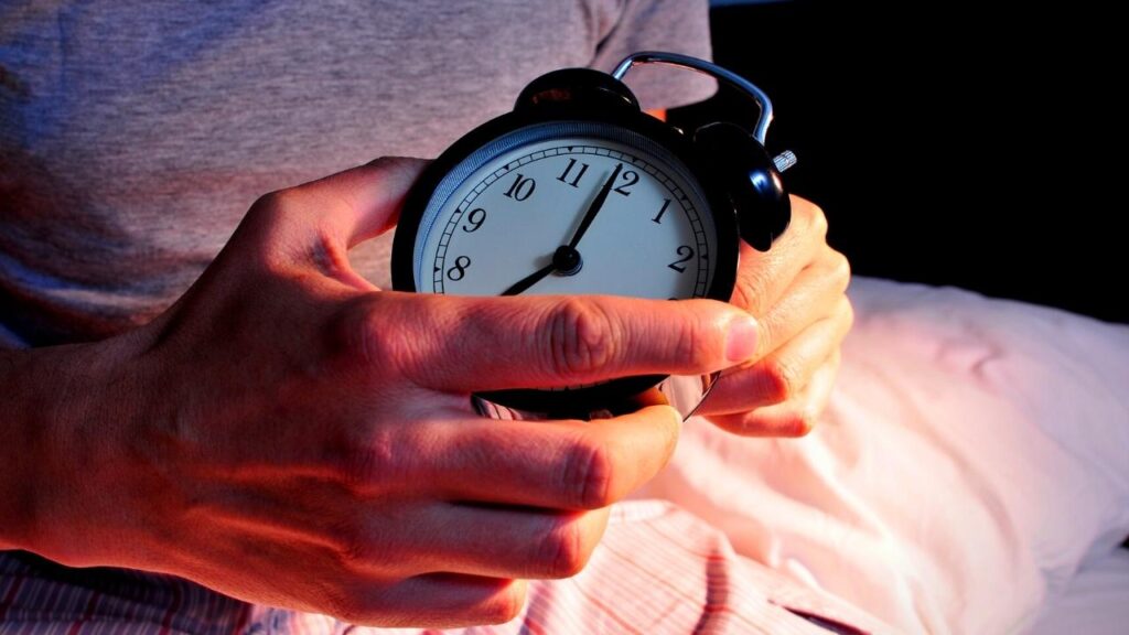 image of hands holding a black alarm clock