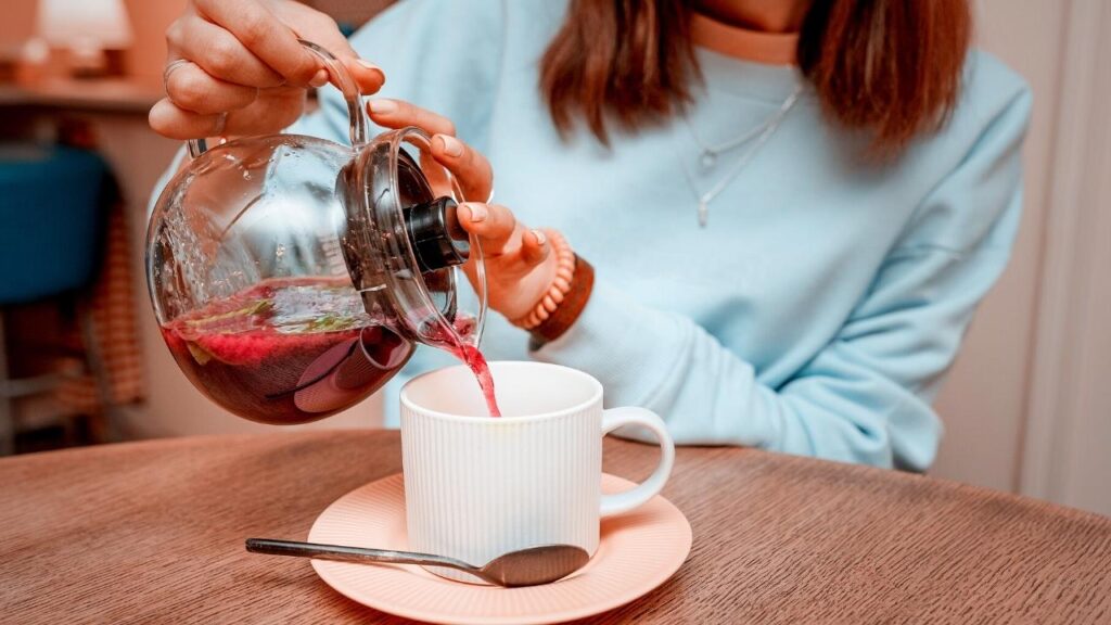 woman pouring fruit tea into a cup