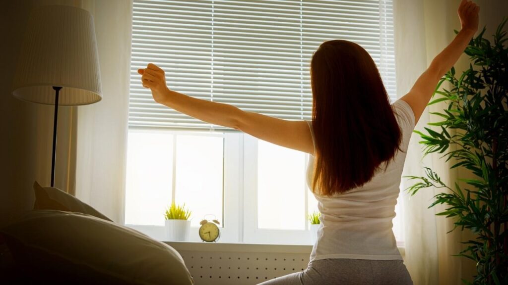 woman sitting on bed with arms outstretched