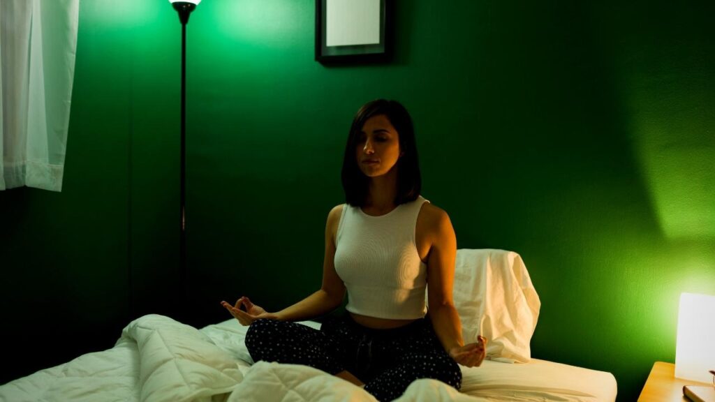 woman doing yoga on bed, green background