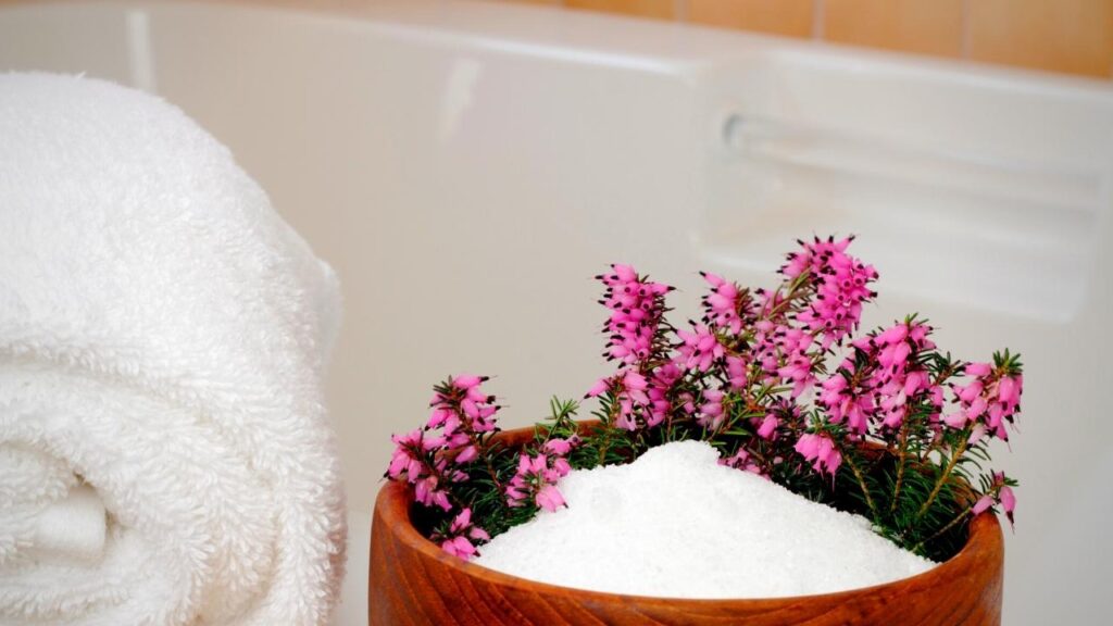 bowl of epsom salts beside white towel on bath