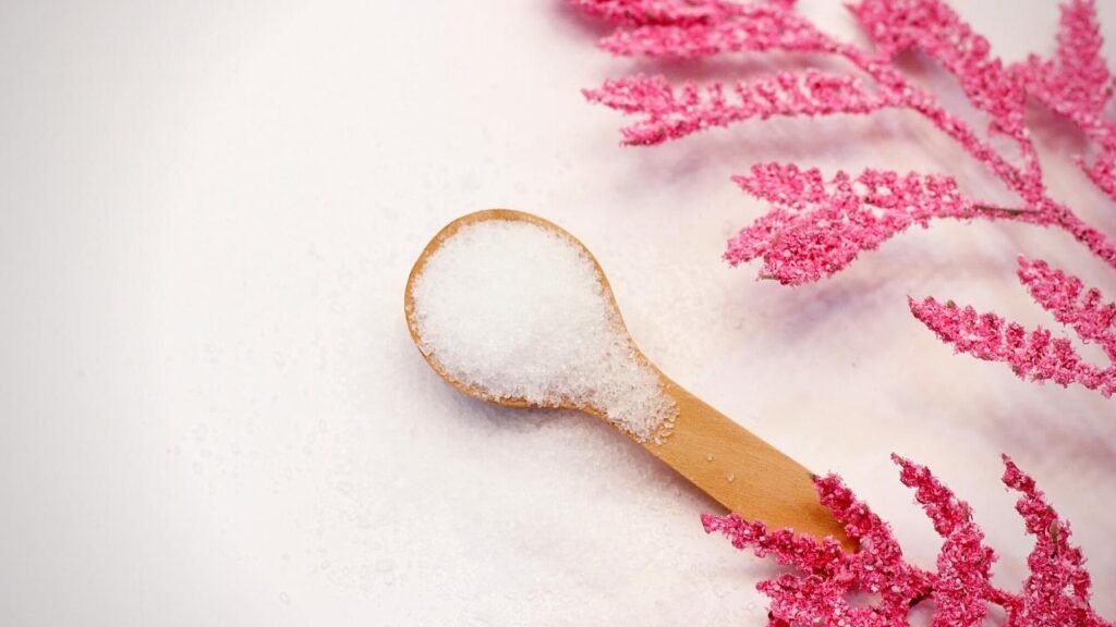 small wooden spoon of epsom salts and pink flowers