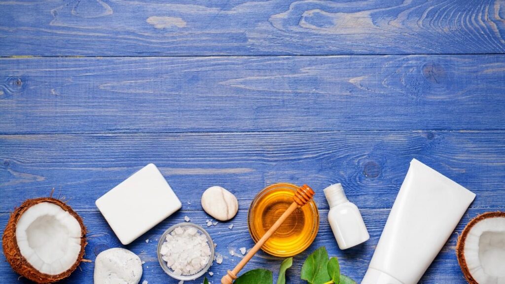 honey, coconut halves, salts and other ingredients on blue background
