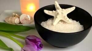black bowl of epsom salts with star fish beside lilac flower