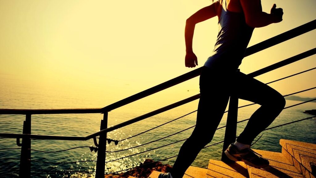 woman running up steps beside the sea