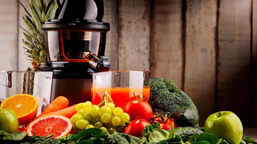 slow juicer surrounded by fruit and veg