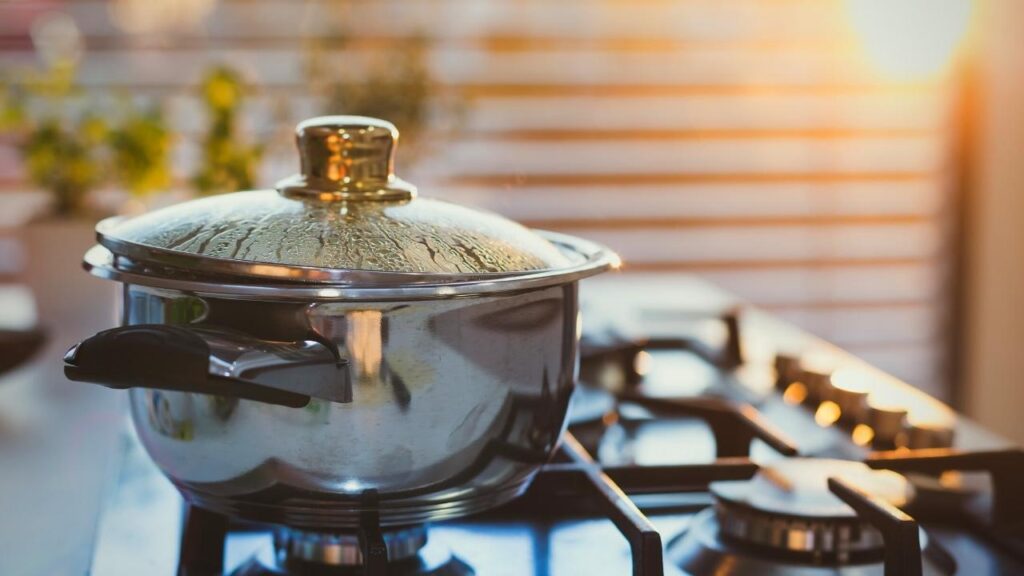 Stainless steel pan with glass lid on cooker