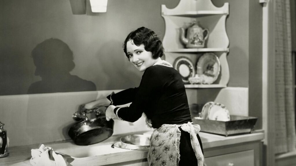 black and white image of woman washing pots in sink