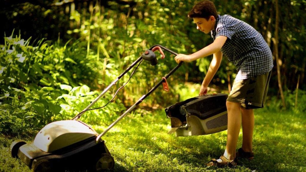 boy putting grass box on lawnmower