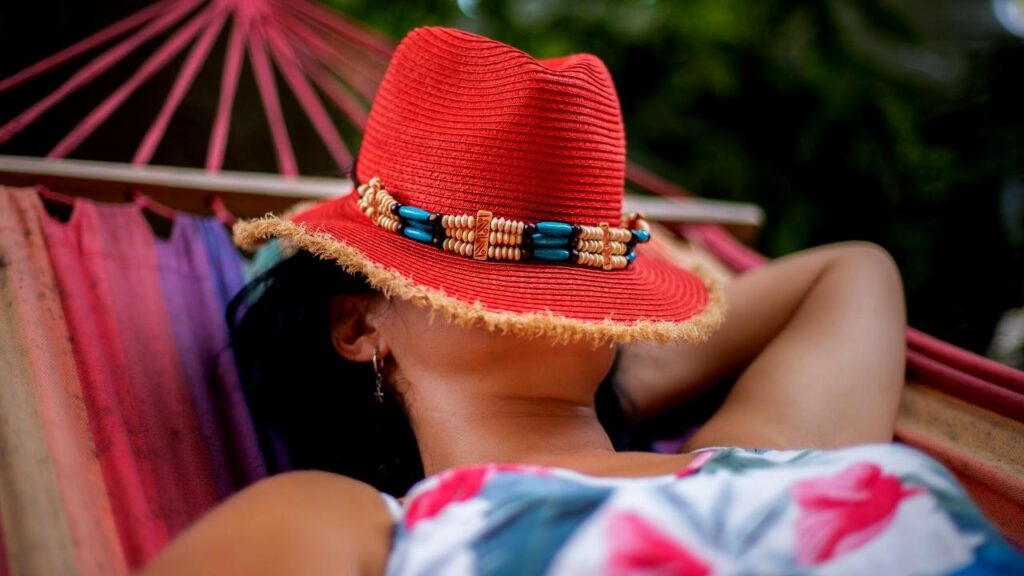 woman with red sun hat relaxing in hammock