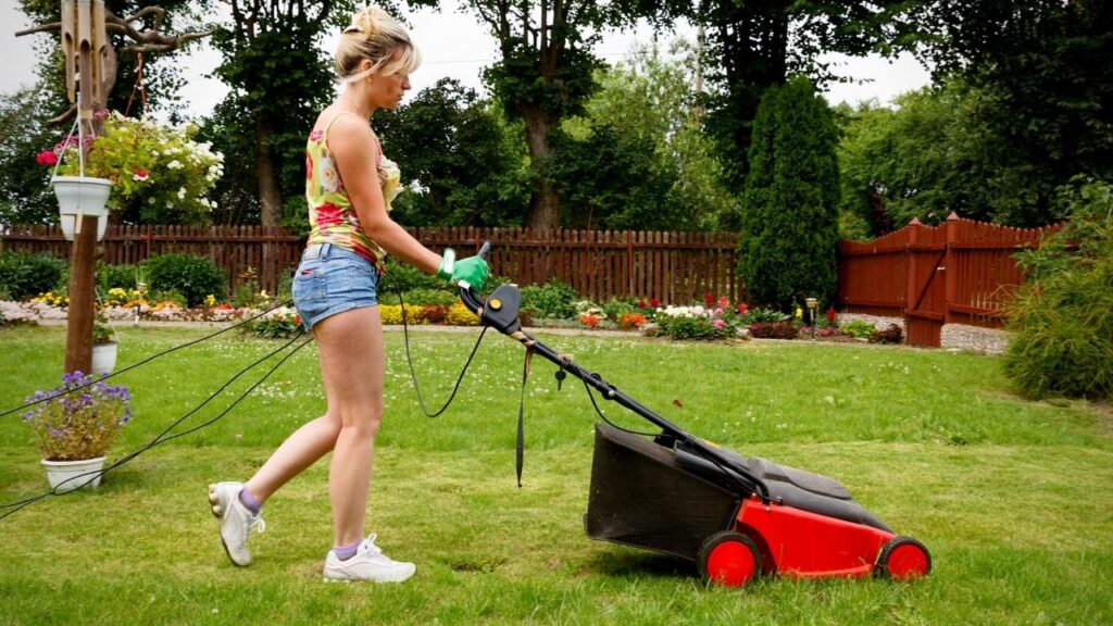woman in shorts cutting lawn with mower